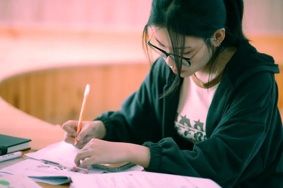 Mahasiswa sedang menulis aplikasi beasiswa di meja belajar